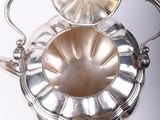an antique silver plated teapot with a lid on a stand
