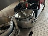 several pots and pans are lined up on a shelf in a kitchen