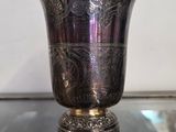 un vase en argent posé sur une table en verre