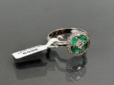 gros plan d'une bague avec une pierre verte et des diamants