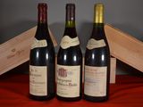 three bottles of wine sit on a red cloth next to a wooden box