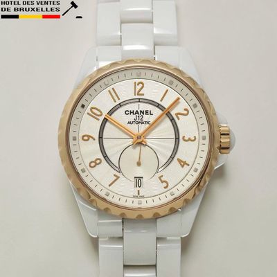 une montre blanche et dorée posée sur une surface blanche