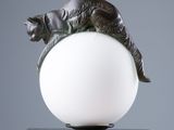 sculpture représentant un chat allongé sur une balle posée sur une table