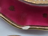 two plates with gold designs on them on a white table