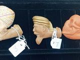three clay figurines of different shapes and sizes are on a shelf