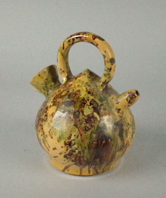 un vase jaune et marron muni d'une anse, posé sur une table