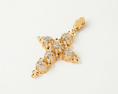 un gros plan d'un pendentif en forme de croix dorée sur fond blanc
