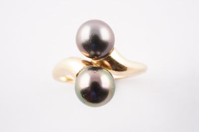 une bague en or sertie d'une perle noire sur fond blanc