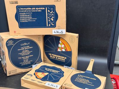 trois boîtes de pizza posées sur un plan de travail, à côté d'un coupe-pizza