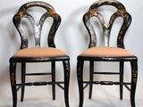 pair of black and gold painted chairs against a white wall