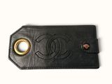 un gros plan sur une étiquette à bagages en cuir noir arborant le logo Chanel