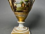 a vase with a painting on it sitting on a table