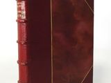 an old red book with a gold binding on a white background