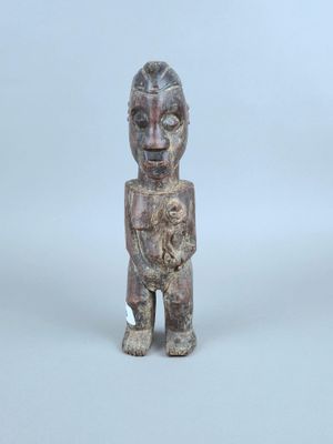 une vieille statue en bois représentant un homme tenant un bébé dans ses bras