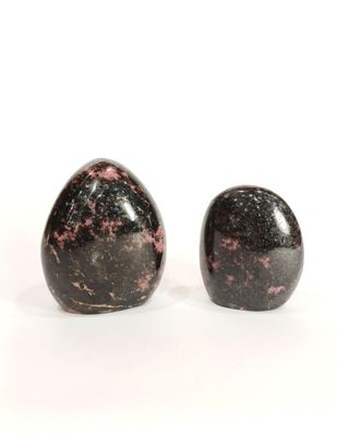 deux pierres noires et roses posées sur une surface blanche