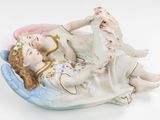 a figurine of two children laying on a pillow