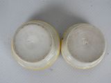 two white and yellow vases sitting on top of a white table
