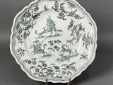 une image représentant une assiette verte et blanche ornée d'un oiseau et de fleurs