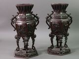 pair of antique chinese vases on pedestals against a gray background