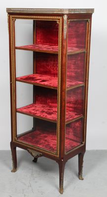 une vitrine ancienne recouverte de velours rouge et ornée de passementeries dorées