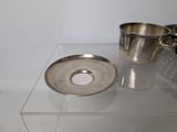a silver cup and saucer sitting on a clear table