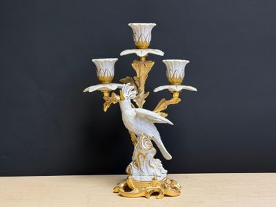 une image représentant un candélabre blanc et doré sur lequel est perché un oiseau