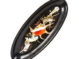une assiette ovale noire ornée d'un poisson doré et de fleurs