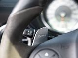 a close up of a steering wheel with a clock in the background