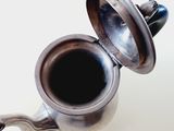 a silver tea pot with a lid on a white table