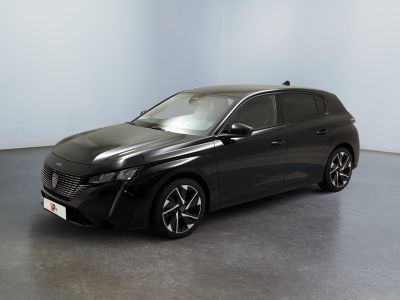 La voiture noire est garée dans une grande pièce aux murs blancs.