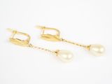 une paire de boucles d'oreilles en perles et or sur fond blanc