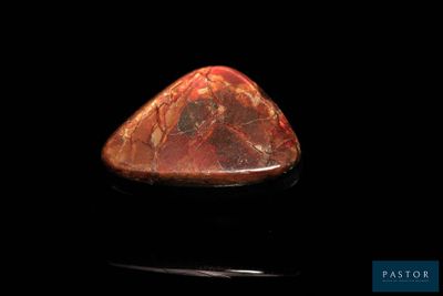 un gros plan d'une pierre rouge sur une surface noire