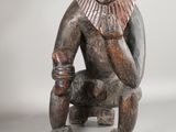 an image of a wooden statue of a man sitting on a stool