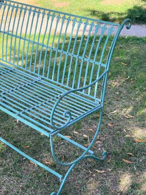 un banc en métal vert posé dans l'herbe du parc