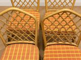 quatre chaises vintage en rotin avec des coussins à carreaux orange et jaunes