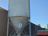 un grand silo blanc posé à côté d'un camion rouge
