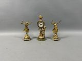 trois figurines dorées surmontées d'une horloge