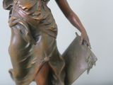a bronze statue of a woman holding a book