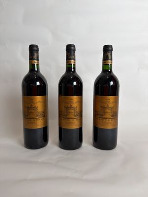 three bottles of wine are lined up on a white surface
