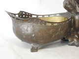 a bronze statue of a lion sitting next to a bowl