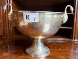 a silver bowl on a wooden table with a painting in the background