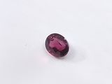 a purple oval shaped gems on a white surface