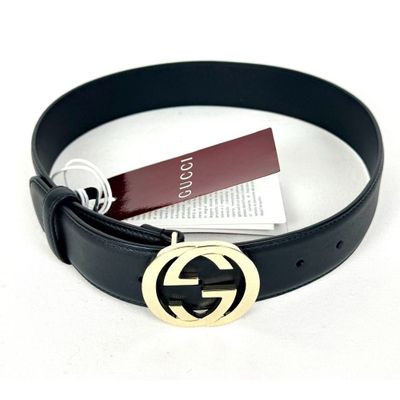 une ceinture en cuir noir avec une boucle dorée et une étiquette
