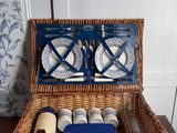 un panier de pique-nique en osier contenant des assiettes et des tasses