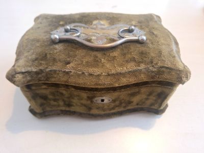 une petite boîte en pierre munie d'une poignée en métal, posée sur une table