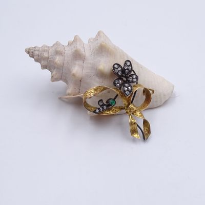 une broche en or ornée d'une fleur verte et blanche