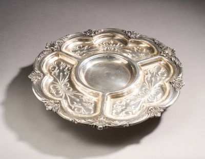 an antique silver plate on a table with a shadow on the ground