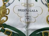 a close up of a green and gold belt on a white shirt