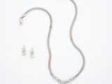 une photo d'un ensemble composé d'un collier et de boucles d'oreilles, posé sur un fond blanc
