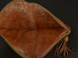 leather pouch with fringes on a black surface with a black background